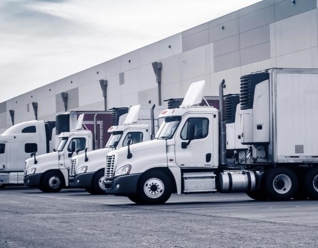 Fleet of refrigerated trailers and class 8 trucks at a warehouse